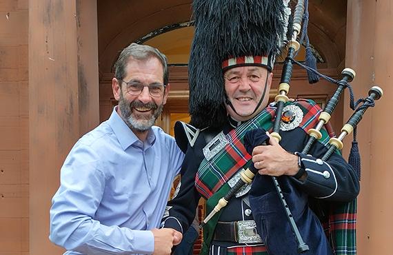 A tour leader posing with and shaking hands with a Scottish Blackguard.